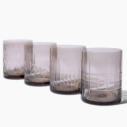 Set of four smoked glass tumblers on a white background