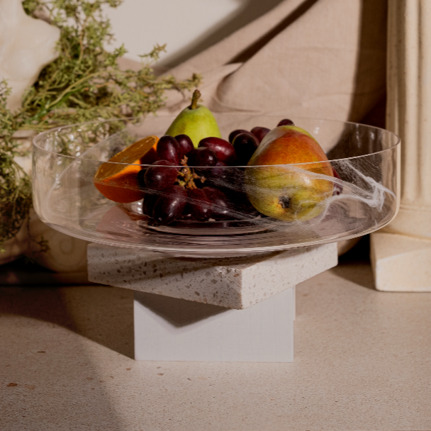 An elegant Alabaster Serving Bowl with a matte finish, filled with fruits like grapes and pears, placed on a stone surface.